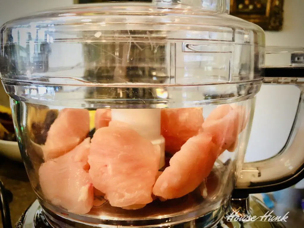 side view of frozen chicken breasts in a food processor