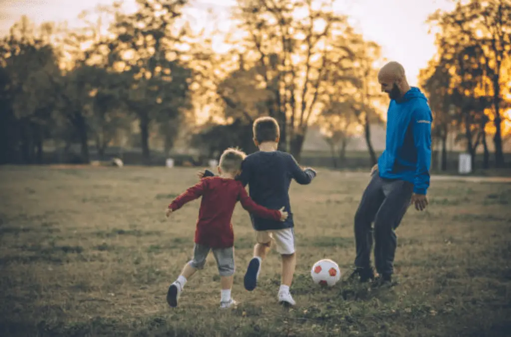 dad playing soccer with kids
