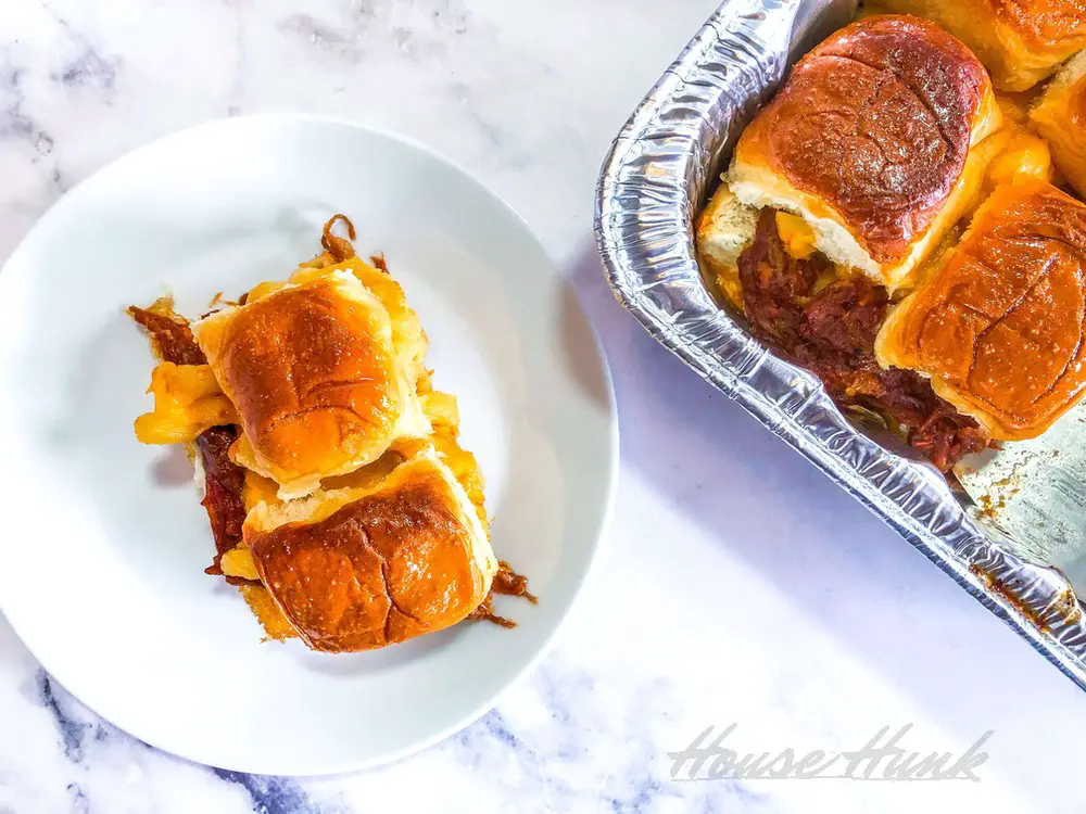 An overhead shot of a plate of the best macaroni and cheese topped pulled pork sliders on a marble countertop