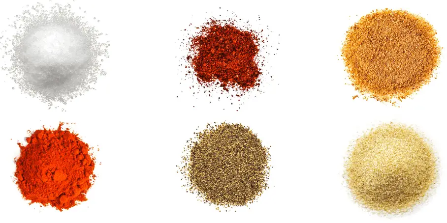 A photorealistic image of ingredients for Homemade Nashville Hot Chicken Seasoning consisting of six piles of different spices and herbs on a white background.