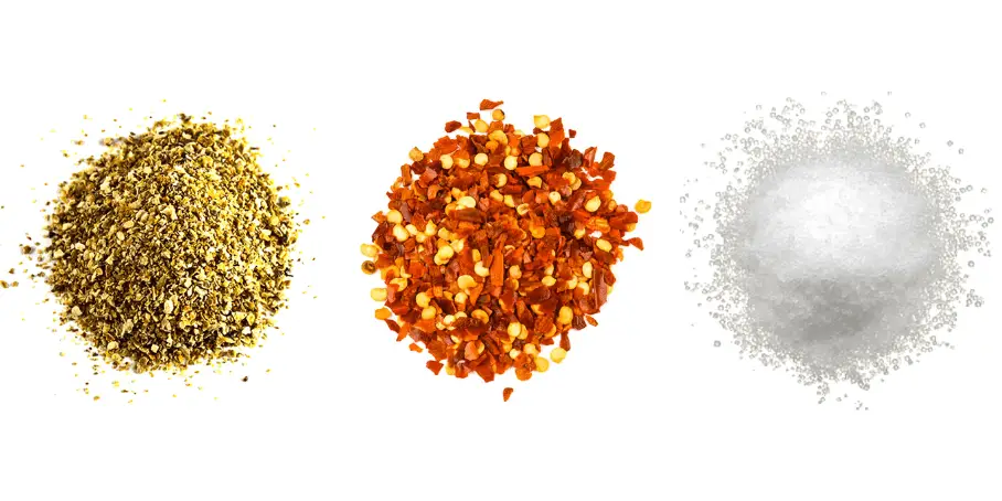 A photorealistic image of ingredients for Homemade Chile-Lime Seasoning consisting of three piles of different spices and herbs on a white background.