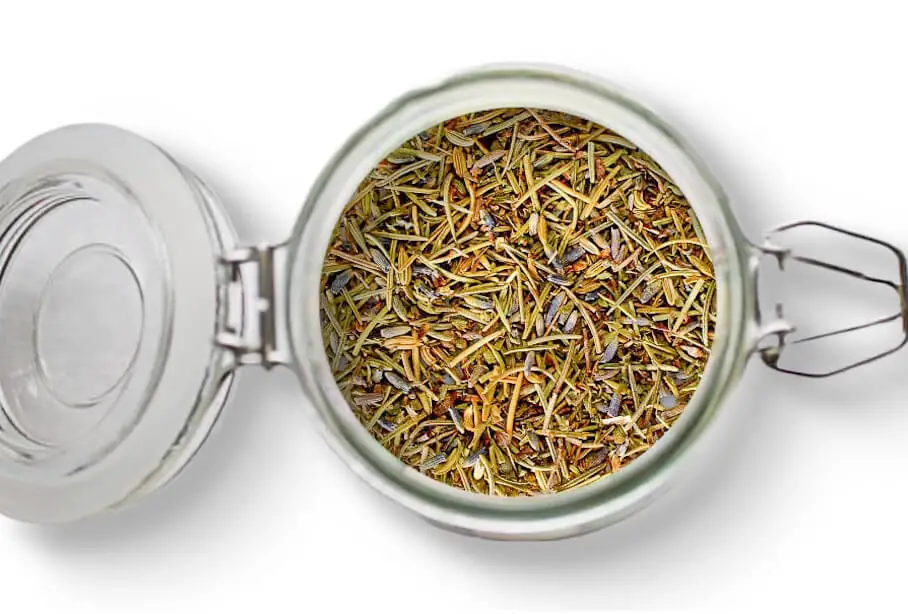 A photo of an open jar of homemade herbs de Provence seasoning on a white background.