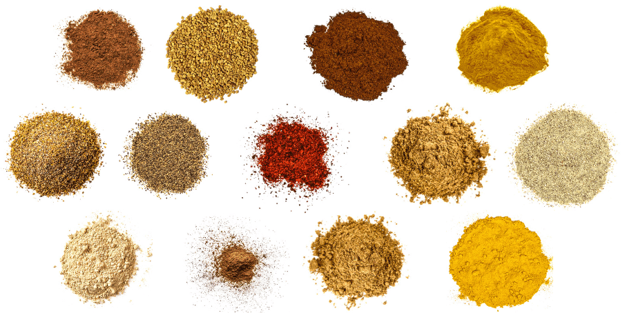 A photorealistic image of ingredients for Homemade Curry Powder consisting of thirteen piles of different spices and herbs on a white background.