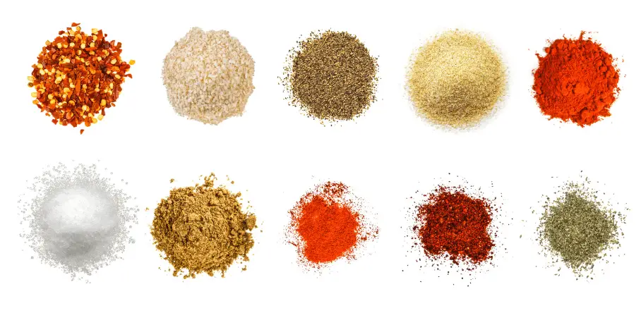 A photorealistic image of ingredients for Homemade Taco Seasoning consisting of ten piles of different spices and herbs on a white background.