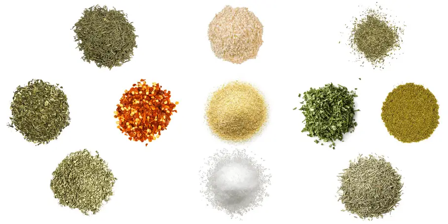 A photorealistic image of ingredients for Homemade Italian Seasoning consisting of eleven piles of different spices and herbs on a white background.
