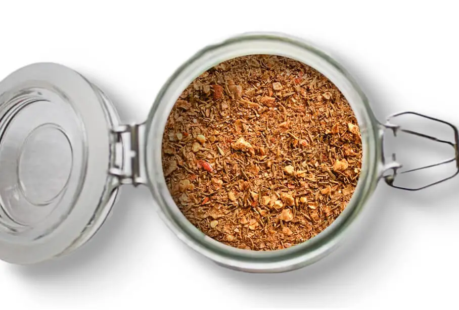 A photo of an open jar of homemade jerk spice seasoning on a white background.