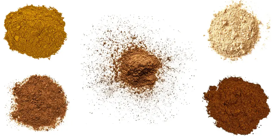 A photorealistic image of ingredients for Homemade Pumpkin Pie Spice Blend consisting of five piles of different spices and herbs on a white background.