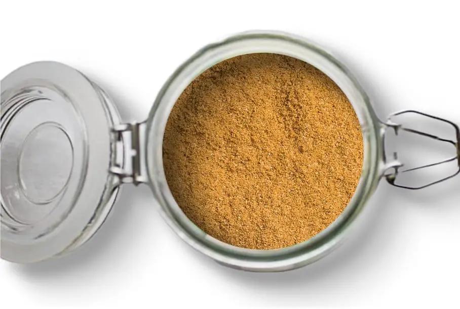 A photo of an open jar of homemade poultry seasoning on a white background.
