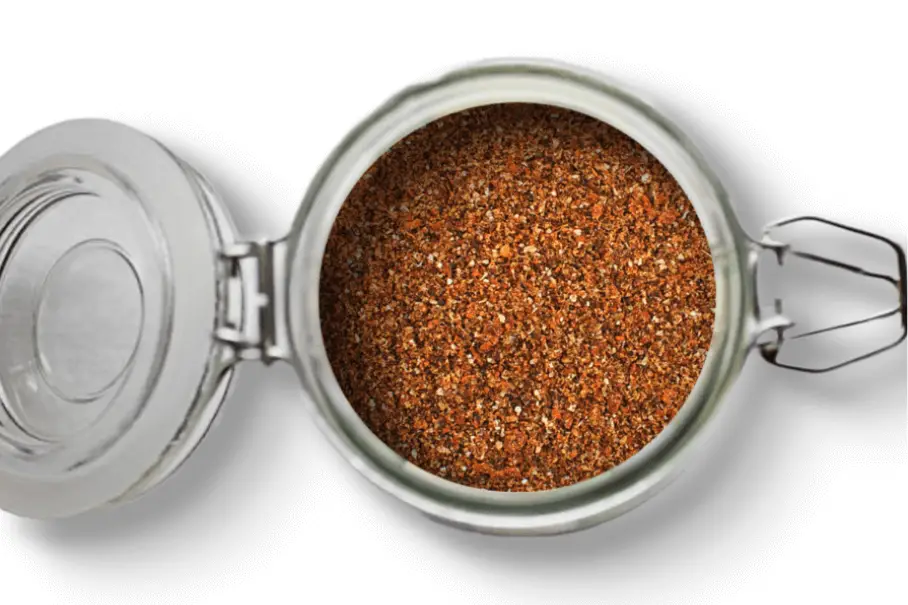 A photo of an open jar of homemade Harissa spice blend on a white background.