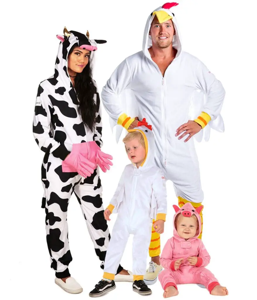 A photo of a group of people wearing animal onesies. The group consists of two adults and two children. The adult on the left is wearing a cow onesie, the adult on the right is wearing a chicken onesie, the child on the left is wearing a sheep onesie, and the child on the right is wearing a pig onesie.