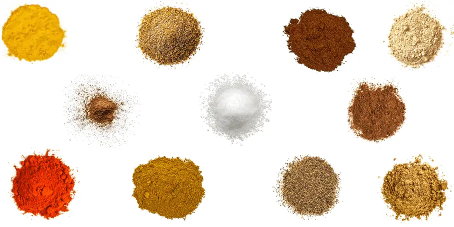 A photorealistic image of ingredients for Homemade Ras El Hanout Seasoning consisting of eleven piles of different spices and herbs on a white background.
