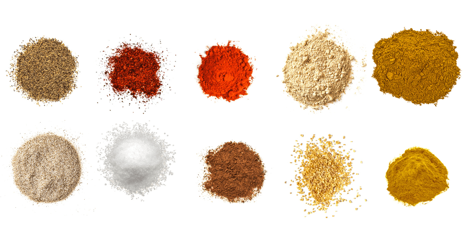 A photorealistic image of ingredients for Homemade Seafood Spice Mix consisting of ten piles of different spices and herbs on a white background.