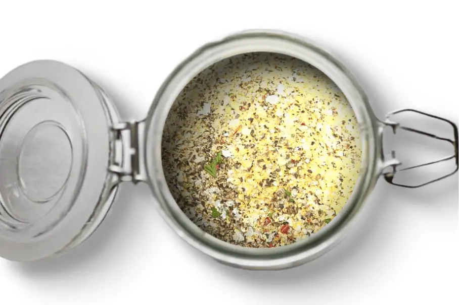 A photo of an open jar of homemade California spice blend on a white background.