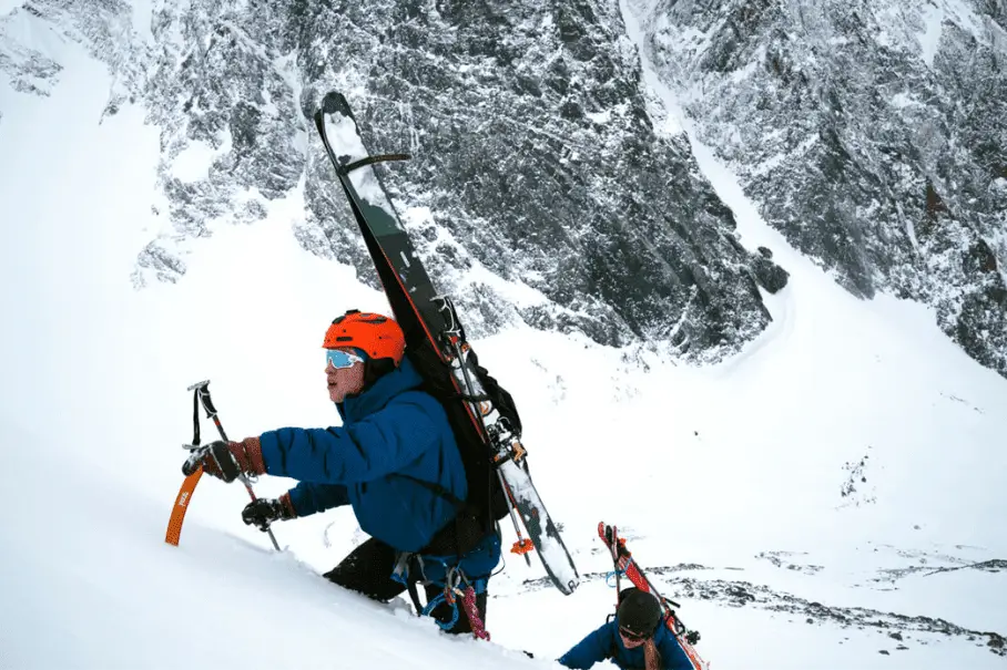 Two skiers climbing up a mountain wearing the Odin Lifa Pro Belay Jacket by Helly Hansen