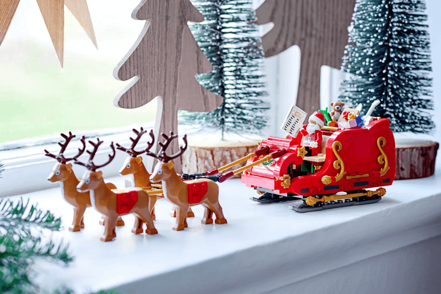 LEGO set of Santa's Sleigh on a window sill with miniature pine trees in the background