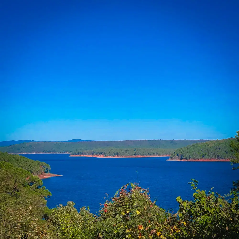 A panoramic view of Lake Greeson with a crystal-clear sky and deep blue water.
