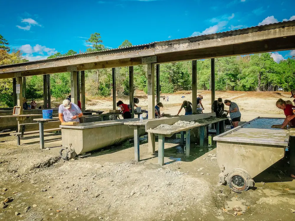 Visitors to Crater of Diamonds State Park searching for gems by sifting through soil and panning for them in troughs of water