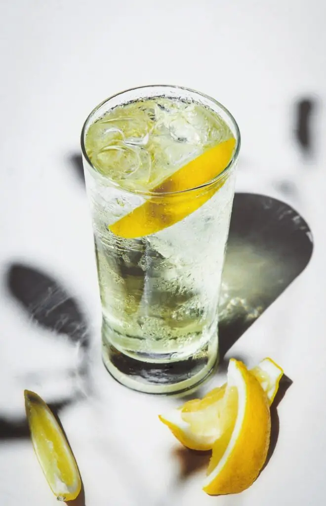 A tall glass of vodka and bitter lemon cocktail with ice cubes and a lemon slice.