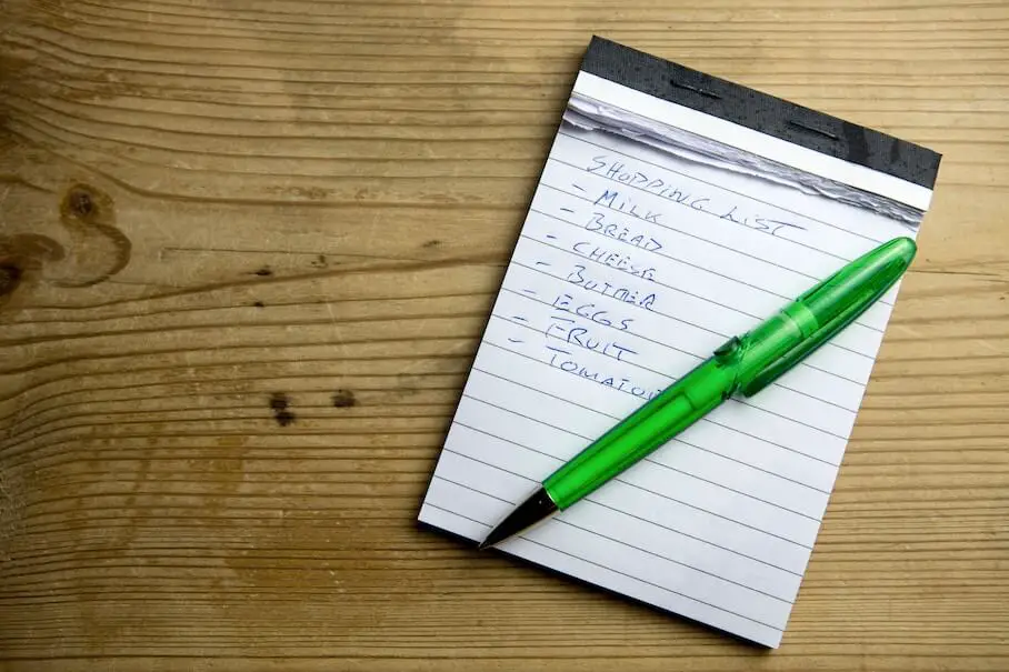 A photo of a shopping list on a notepad with a green pen.