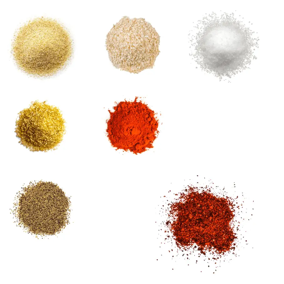 A photorealistic image of ingredients for Homemade Barbecue Chicken Seasoning consisting of seven piles of different spices and herbs on a white background.