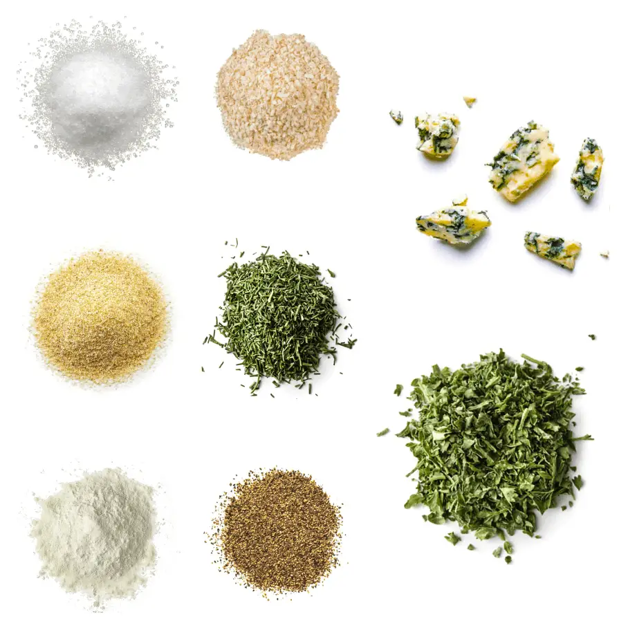 A photorealistic image of ingredients for Homemade Blue Cheese Seasoning consisting of eight piles of different spices and herbs on a white background.