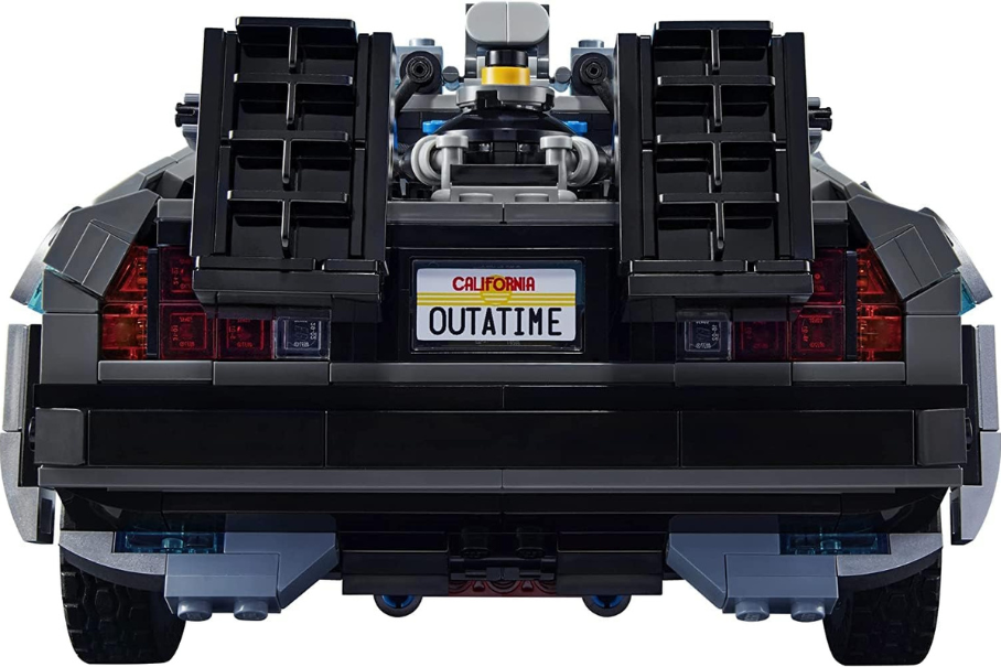 The rear of a black DeLorean car with a California license plate that reads “OUTATIME”. The car has red taillights, a silver exhaust pipe, a silver bumper, a blue undercarriage, a black spoiler, two black vents, and a silver engine.