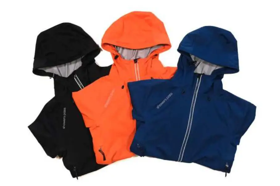 Three hooded jackets in black, orange, and blue are arranged in a triangle on a white background. The jackets have zippers and drawstrings.
