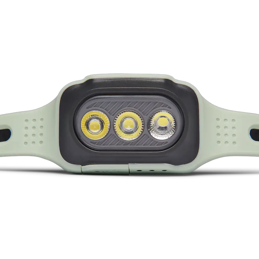 A headlamp with a white body and a black front panel. The front panel has three yellow LED lights in a horizontal row. The headlamp has a perforated strap for wearing it on the head. The background is a solid gray color.